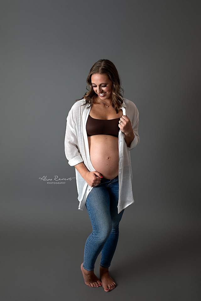 Intimate studio maternity photography in Wheeling, IL, featuring an expecting Mom in a casual white open button-down shirt and jeans.