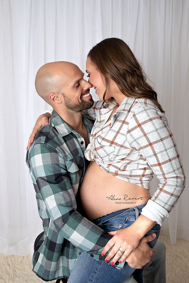 Intimate studio maternity photography in Wheeling, IL, featuring a couple in casual flannel shirts and jeans.