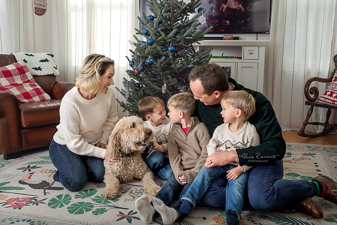 Family laughing together during an in-home holiday tree decorating session.”