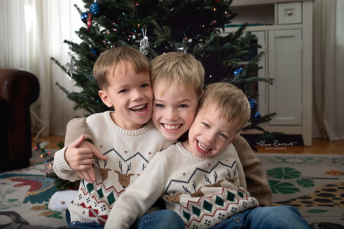Kids laughing and hugging during an in-home  lifestyle holiday tree decorating session with Alina Renert Photography, Wheeling, IL. 