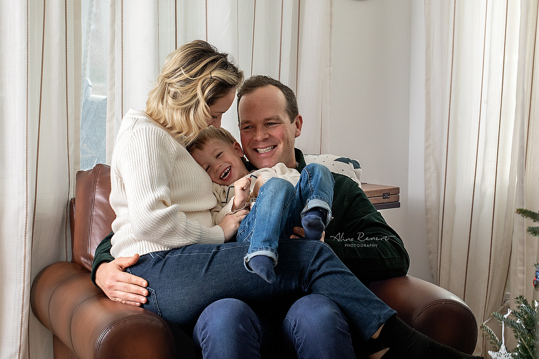 Parents and kids snuggling during an in-home lifestyle holiday family photography session with Alina Renert, Wheeling, IL. 
