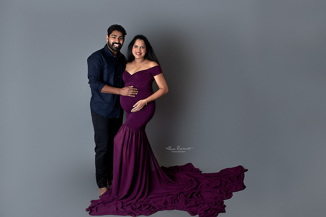 Maternity couples portraits in a Northwest Chicago suburbs studio with a fitted, flowing gown and a neutral backdrop.