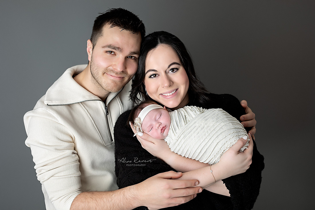 Mom & Dad holding newborn baby girl in a maroon lace outfit, studio newborn session Wheeling, Illinois.