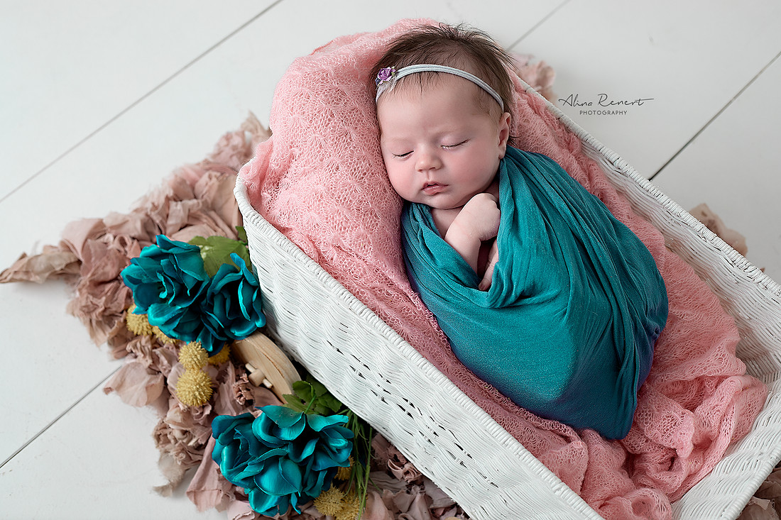 Newborn baby girl wrapped in teal in a white basket, professional newborn photography Chicago.