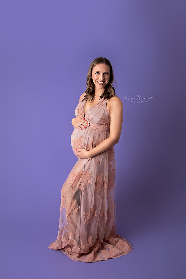 Sultry and sexy maternity portraits in a Northwest Chicago suburbs studio with a sheer lace gown and a purple backdrop.